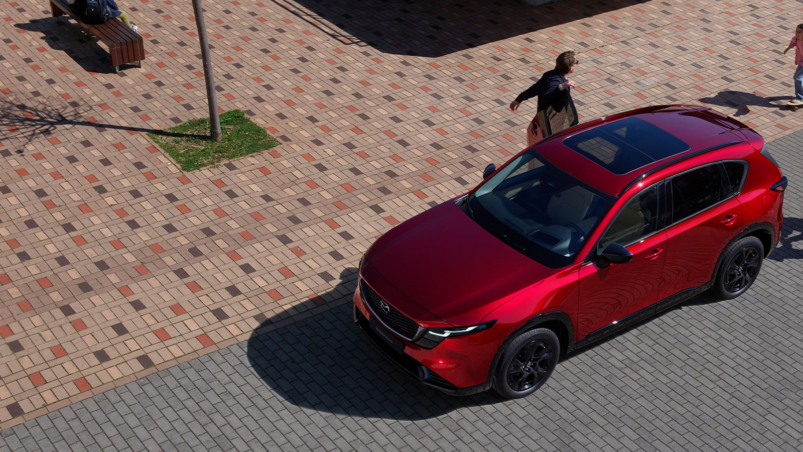 Profil avant latéral d'un Mazda CX-5 rouge vibrant cristal, garé alors qu'un homme en sort.