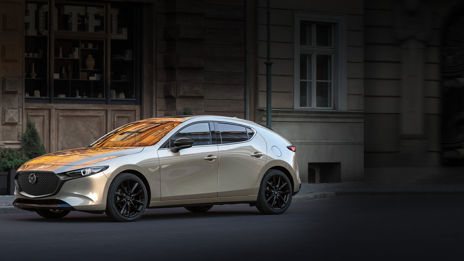 A platinum Mazda3 Sport parked on the street.