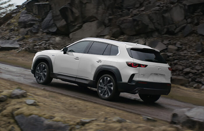 A white HEV drives uphill in rocky, mountainous terrain. 