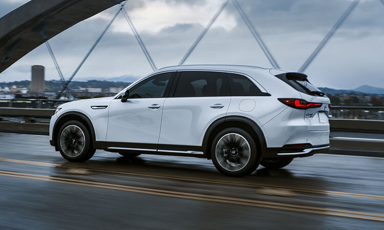 Un CX-90 hybride rechargeable traverse la route sur un pont suspendu. 