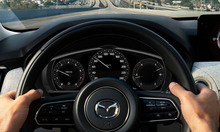 Point de vue d’un conducteur avec les mains sur le volant dans un véhicule en mouvement.
