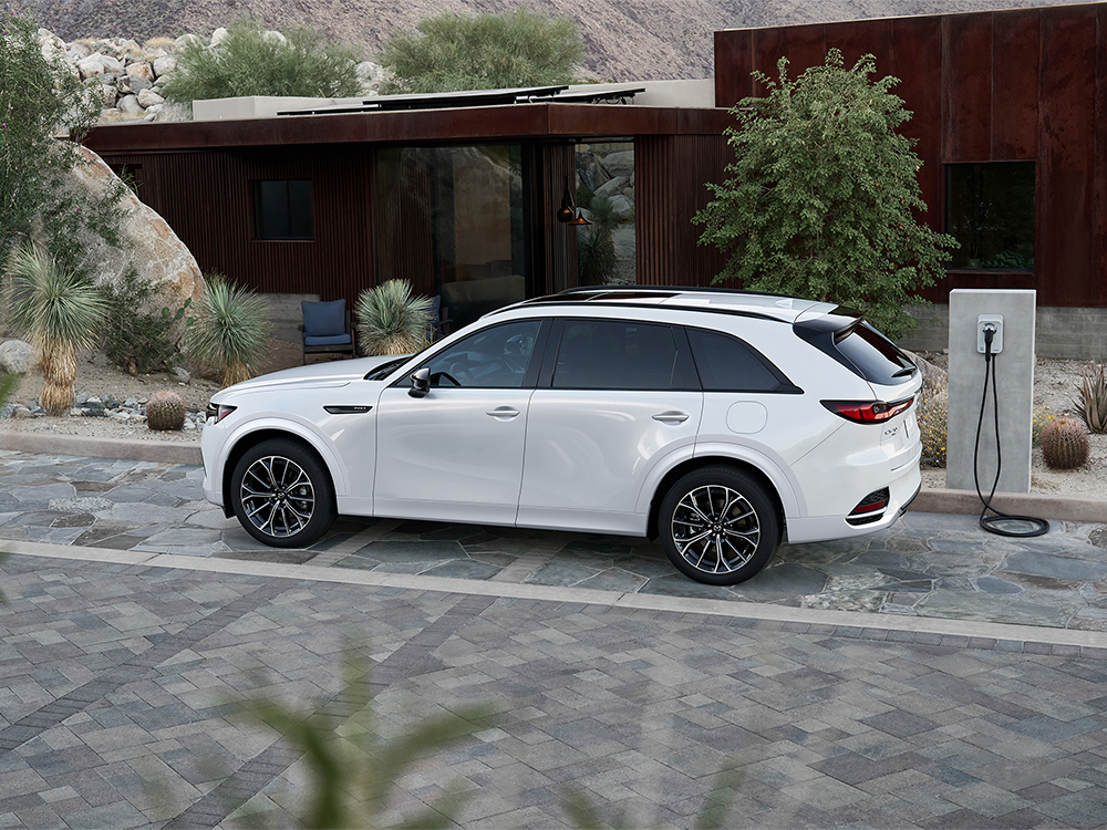 Un conducteur se tourne et regarde en arrière en marchant vers un véhicule électrique MX-30. 