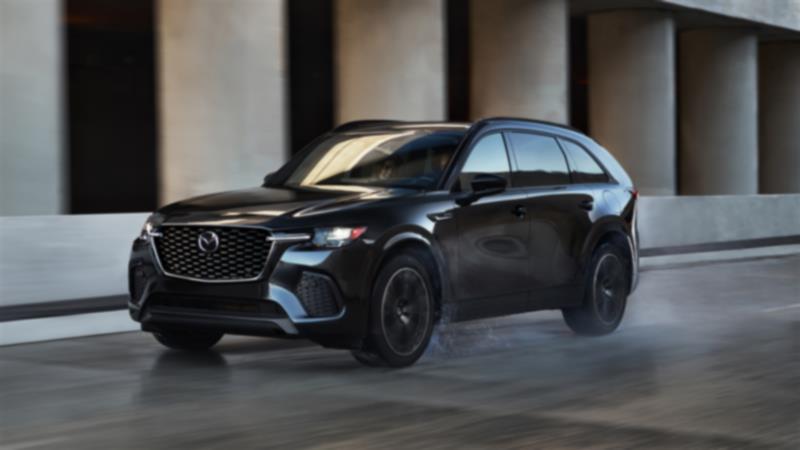 Mazda6 grise sur une pente d’autoroute avec des arbres et des collines flous en arrière-plan. 