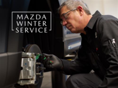 A Mazda technician working on a vehicle's brakes