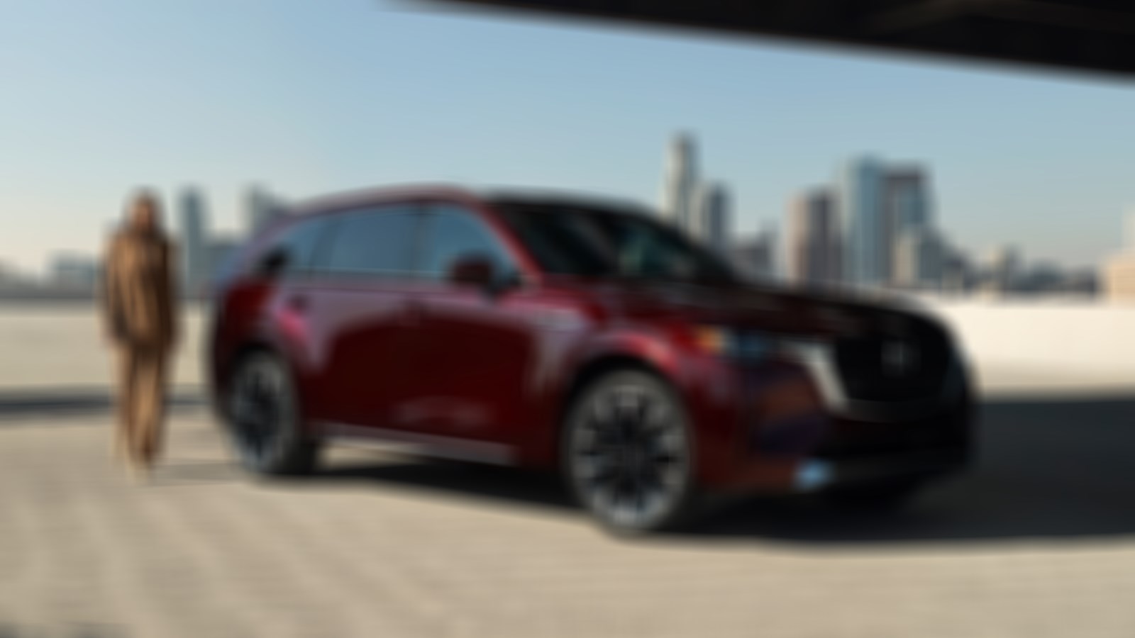 Woman in tan coloured suit approaches the passenger side of parked, Artisan Red CX-90.