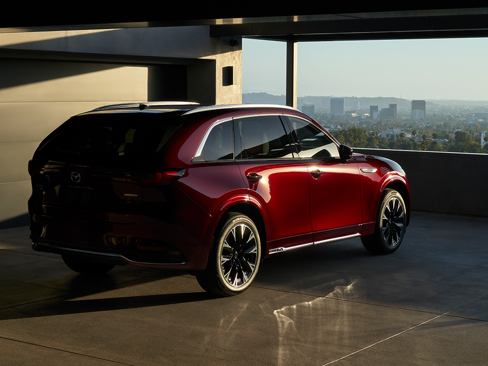 Artisan Red Cx-90 parked in parking garage overlooks a cityscape at sunset.
