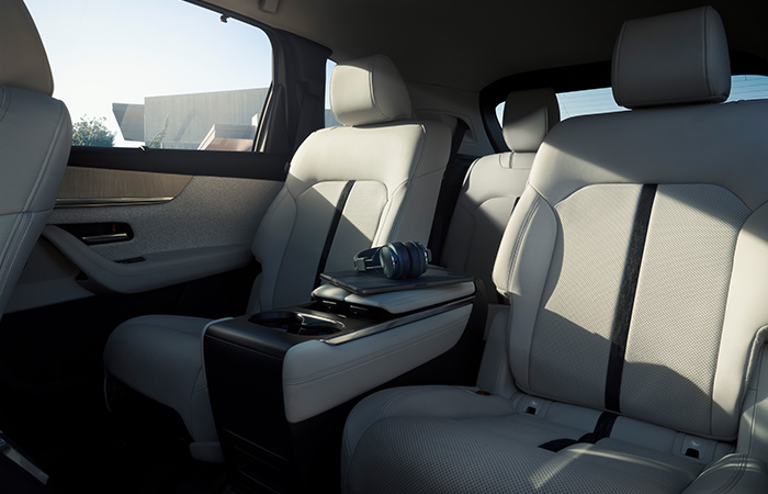 Driver side view of full dash and center console inside the CX-90, sun and trees cast a shadow into the interior. 