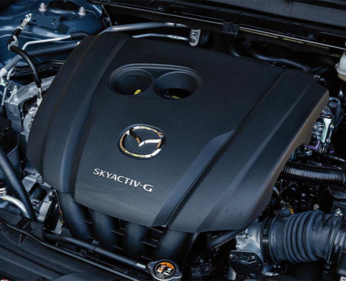 À l’intérieur du capot du CX-30, un couvercle de moteur avec le logo Mazda et l’insigne Skyactiv-G. 