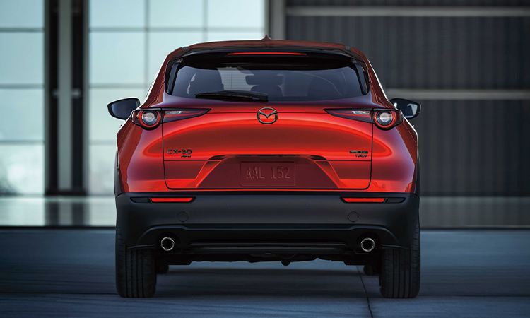 Un CX-30 circulant sur une route de montagne; vue intérieure à partir des sièges arrière vers le conducteur et le passager avant. 