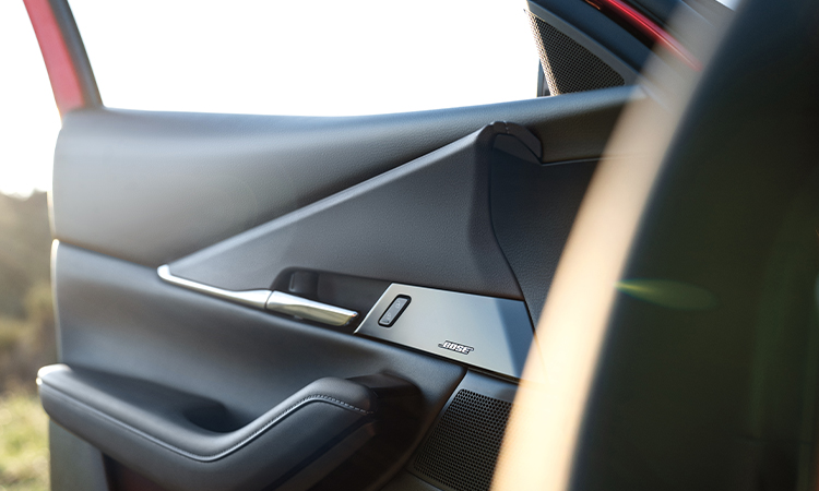 Gros plan d’une femme conduisant un CX-30 à travers la vitre avant côté passager.   