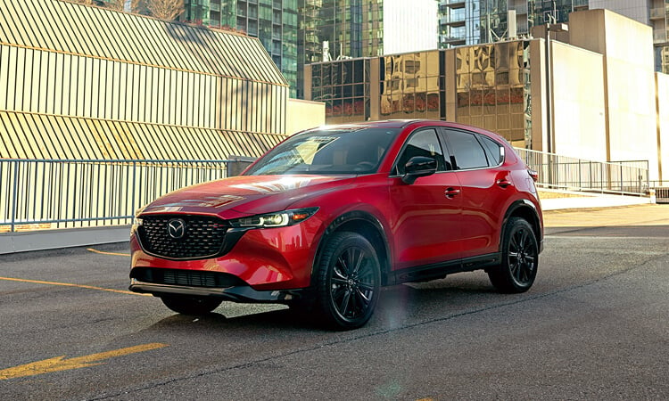 Un CX-5 rouge vibrant cristal métallisé garé au dernier étage d’un stationnement, à la lumière du jour.