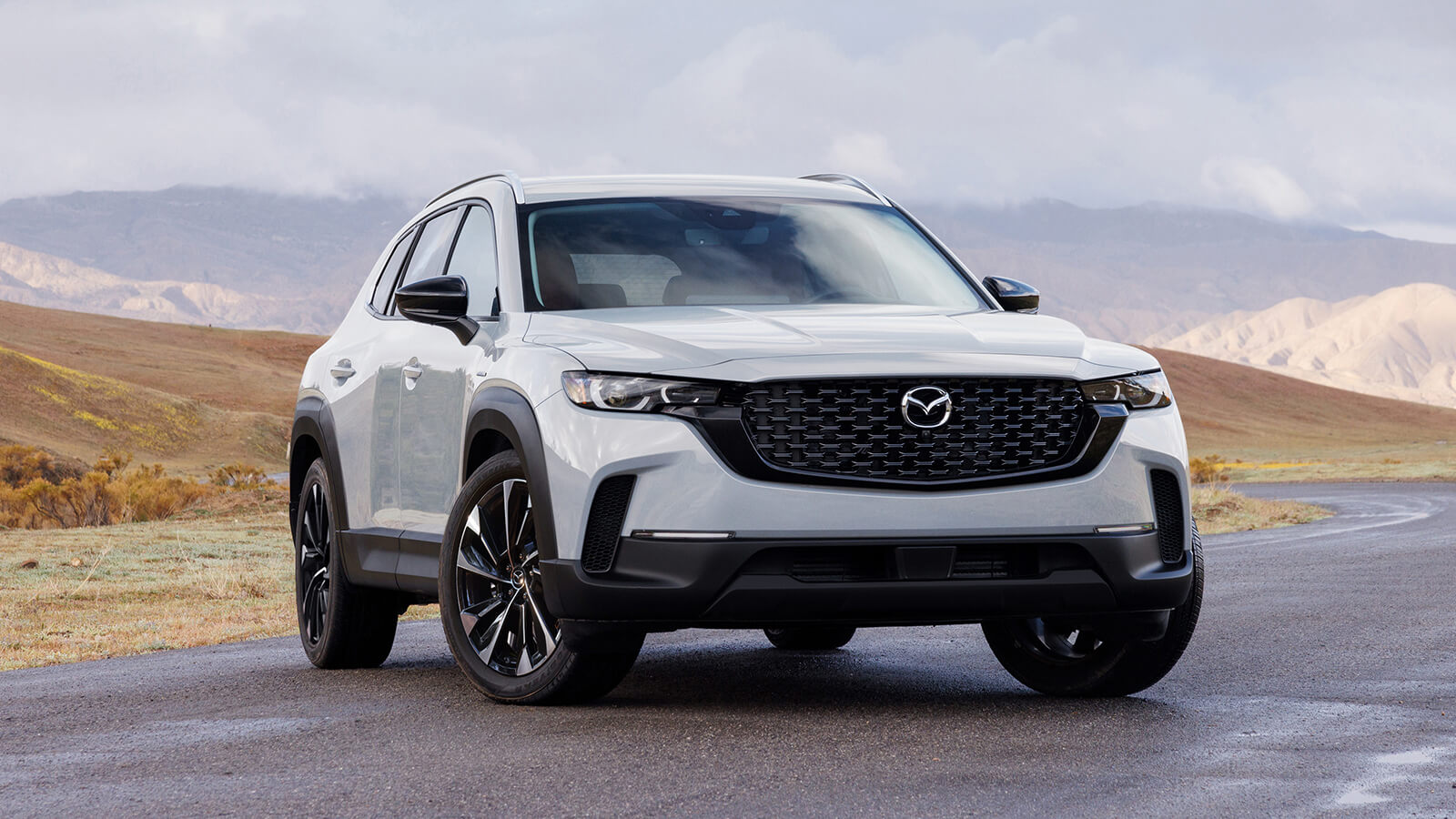 Wind Chill Pearl 2025 Mazda CX-50 Hybrid is parked 7/8 front on in tundra environment. Hills and mountains in background.