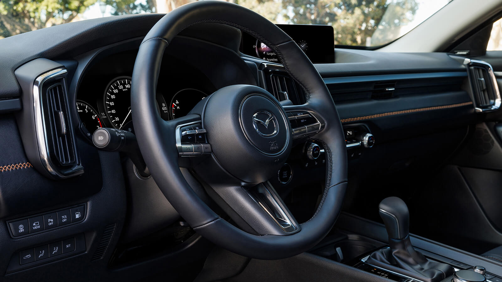 Gros plan du volant, de la planche de bord, de la console, du levier de vitesses et des écrans dans un CX-50 hybride.