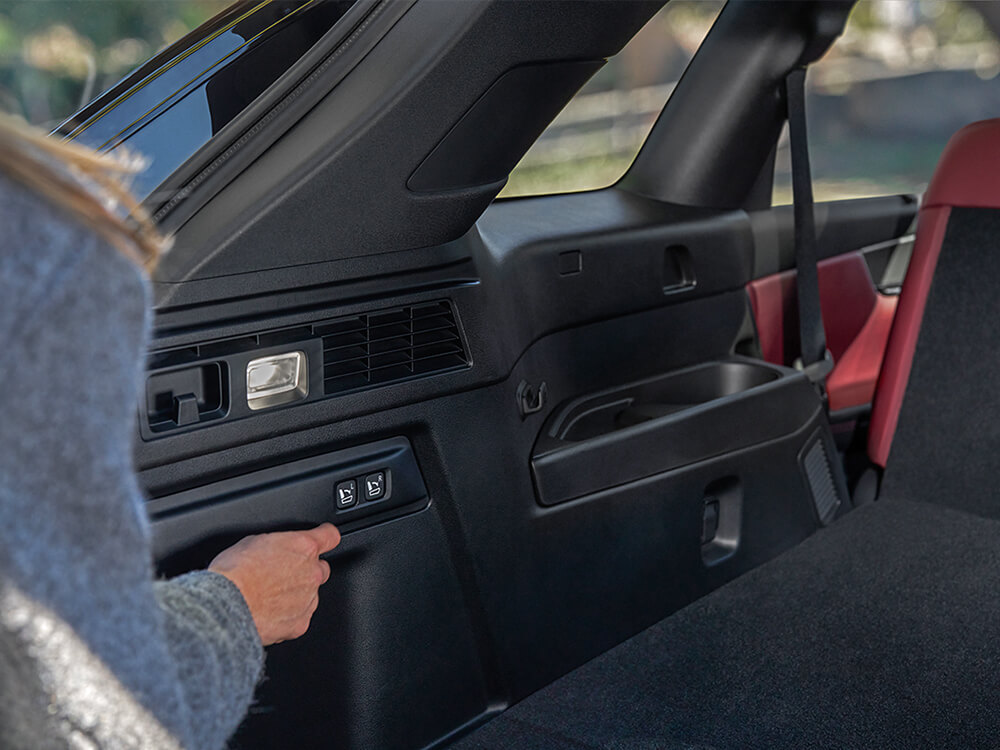 Shot of a driver activating buttons in the back of the CX-70 that automatically lift and lower the second row.