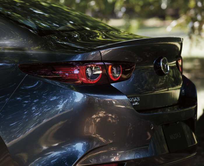 Close-up of Machine Grey Metallic Mazda3 sedan rear profile. 