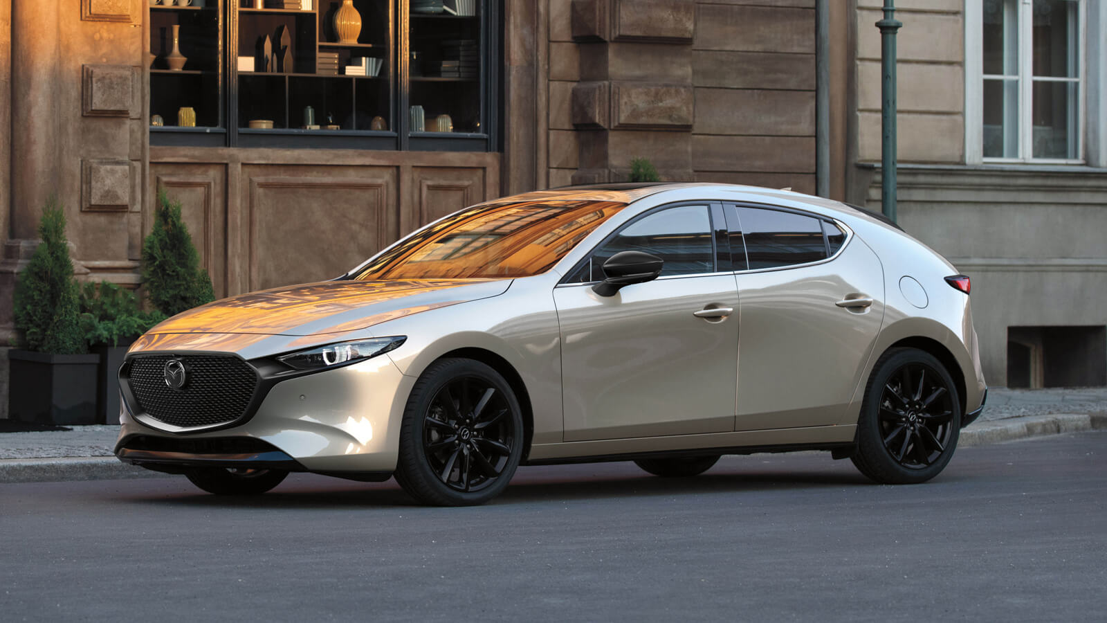 Profile shot of Mazda3 Sport parked in front of shops.