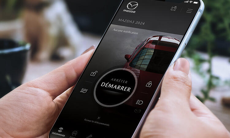 Des mains tiennent un téléphone intelligent avec l’appli MyMazda. 