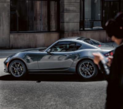 Une MX-5 RF aux reflets métallisés miroitants, garée dans une rue urbaine.