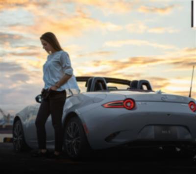 Driver with their hand in their pocket stands next to a silver MX-5 ST