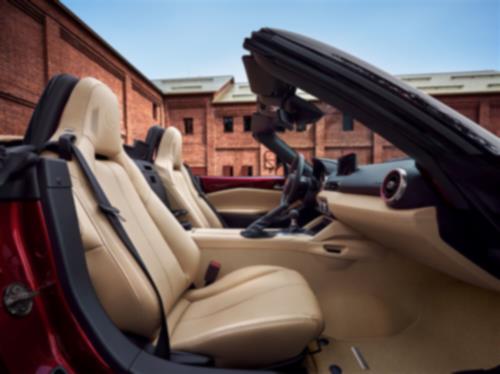 View from the passenger side of the MX-5 ST 35th Anniversary Edition with its top down in front of a building. 