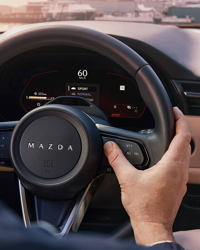 Hand activating a steering wheel control in the Mazda CX-5.