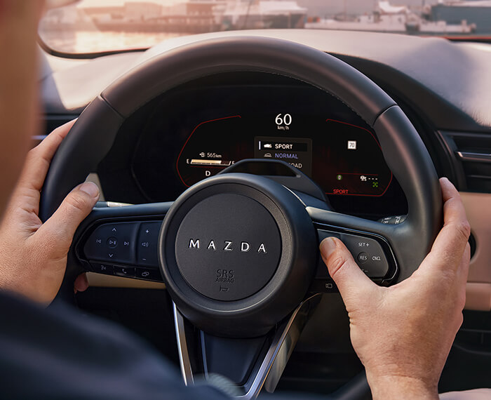 Une main activant une commande au volant du Mazda CX-5.