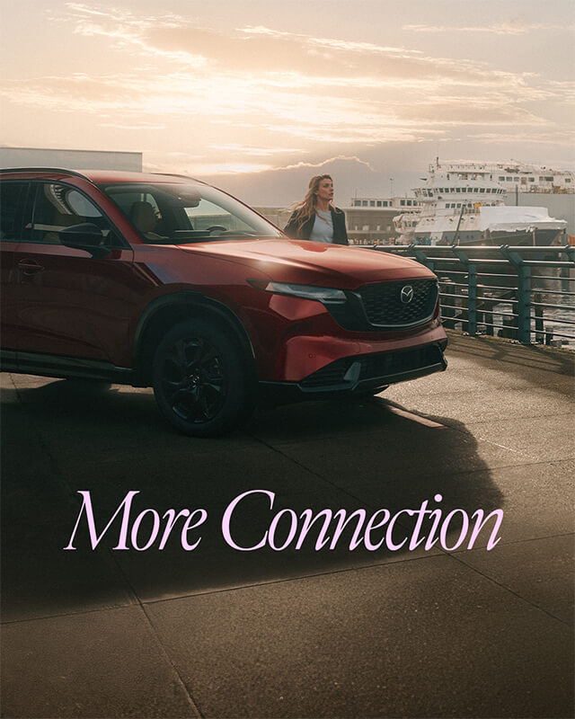 Mazda CX-5 parked by the waterfront with a women standing beside it.