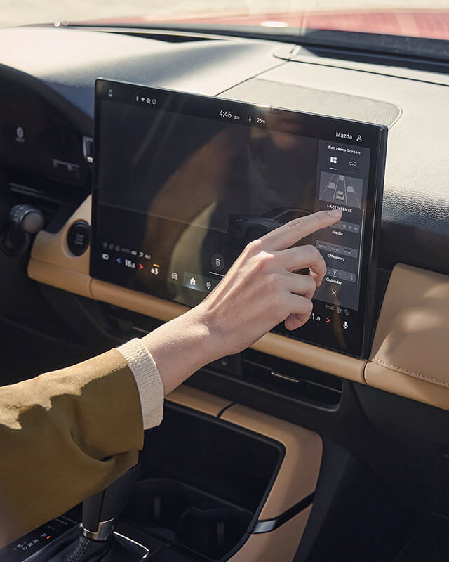 Hand using the Mazda CX-5 centre touchscreen display.