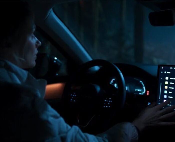 Interior view of a woman driving a Mazda CX-5 with blue ambient lighting.