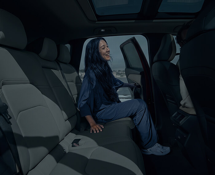 Interior view of a Mazda CX-5 with a woman entering the rear seat from the opposite side.