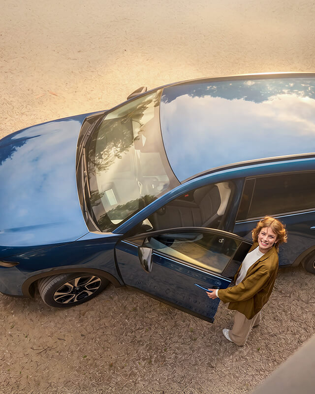 Woman looking up while entering the driver’s side of a Navy Blue Mica Mazda CX-5.