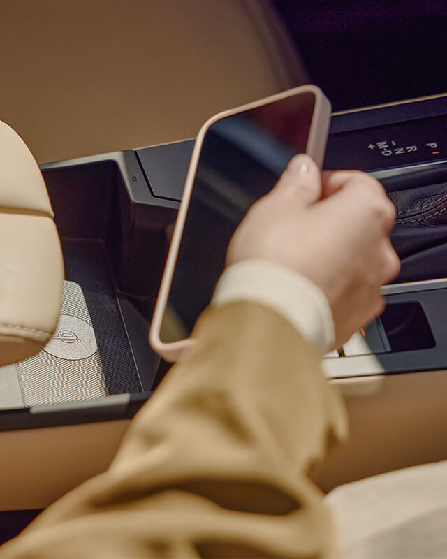 Hand taking a phone from the centre console of a Mazda CX-5.