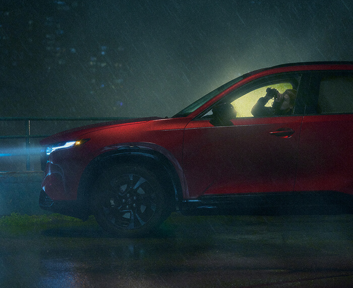 Side profile of a Mazda CX-5 driving on a misty road with headlights on.