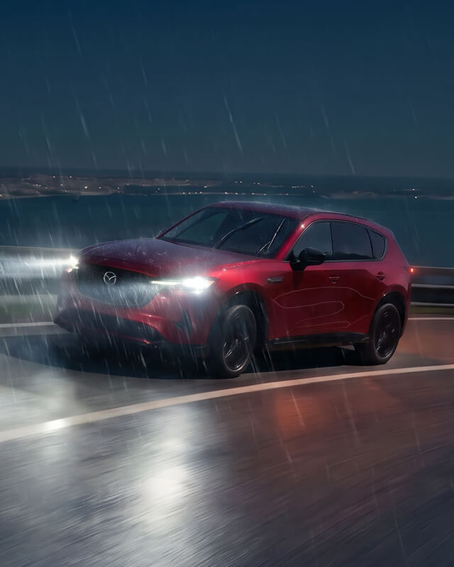 Mazda CX-5 driving on a winding road in heavy rain at night.