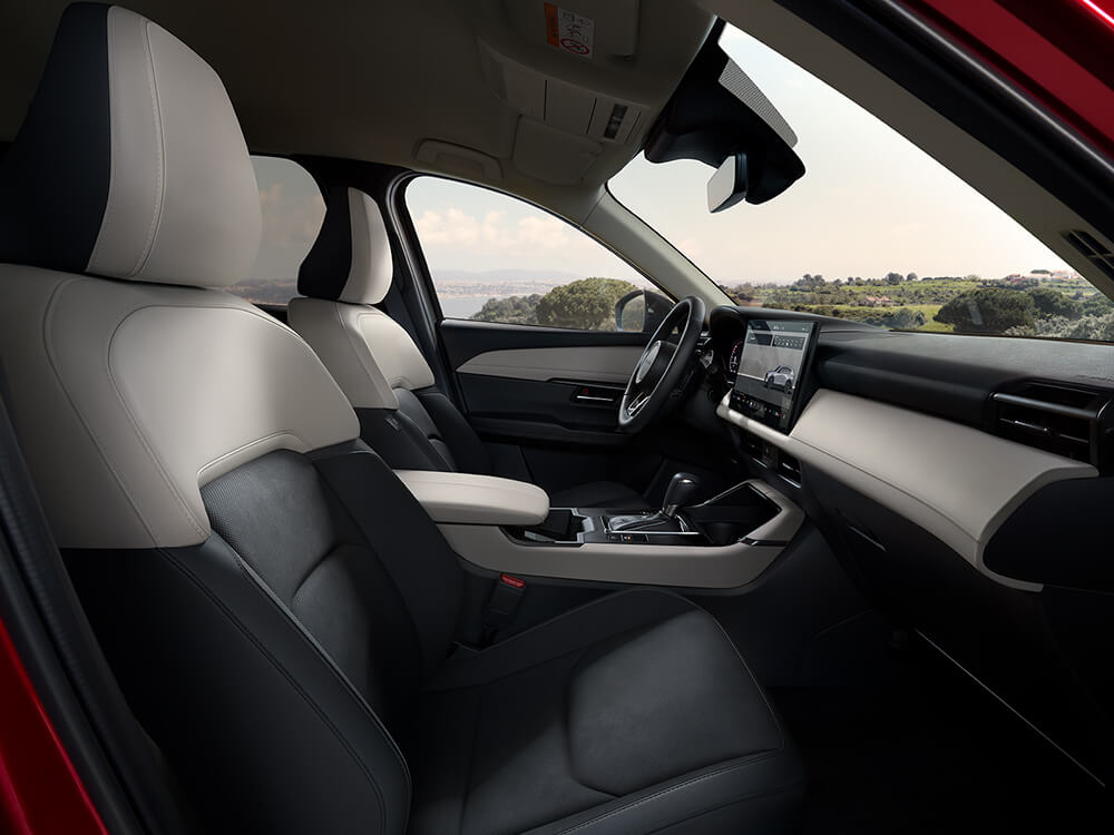 Intérieur d'un Mazda vu depuis la porte côté passager, en regardant vers le côté conducteur, avec une étendue d'eau visible à travers la fenêtre.