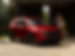Front side profile of a Soul Red Crystal Mazda CX-5 parked in a driveway with a man and woman standing beside it.