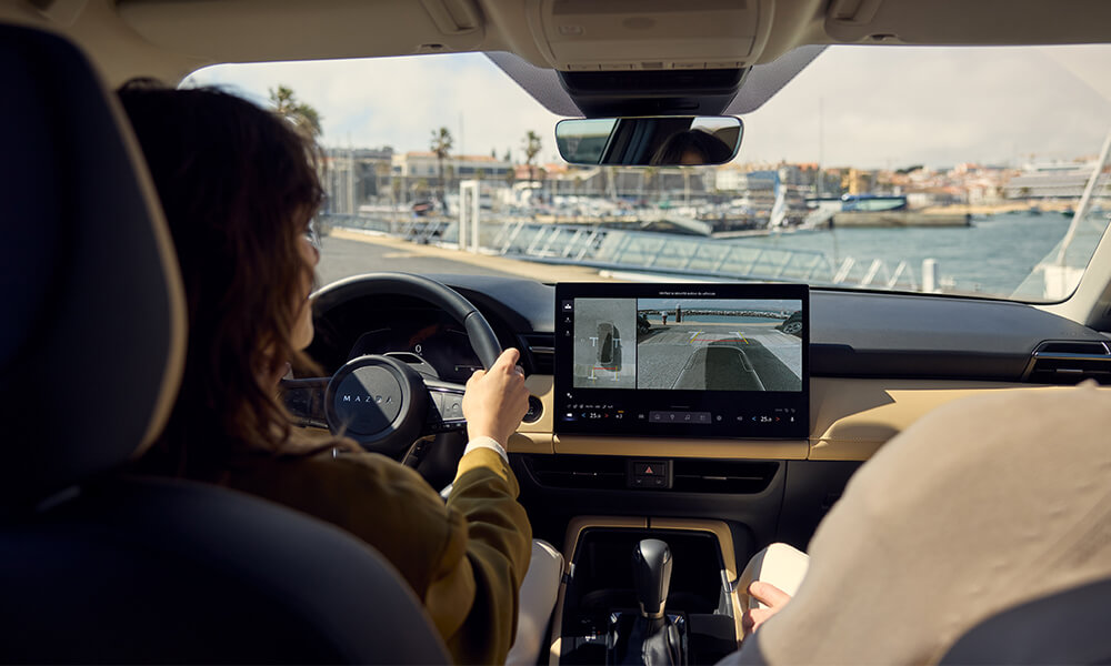 Une femme ouvre la portière côté conducteur d’un Mazda CX-30 rouge vibrant cristal métallisé