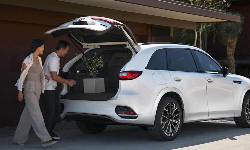 Woman and man putting a plant into the open trunk of the CX-70.