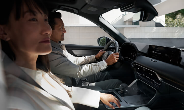 Side profile of a woman and man driving the CX-70.