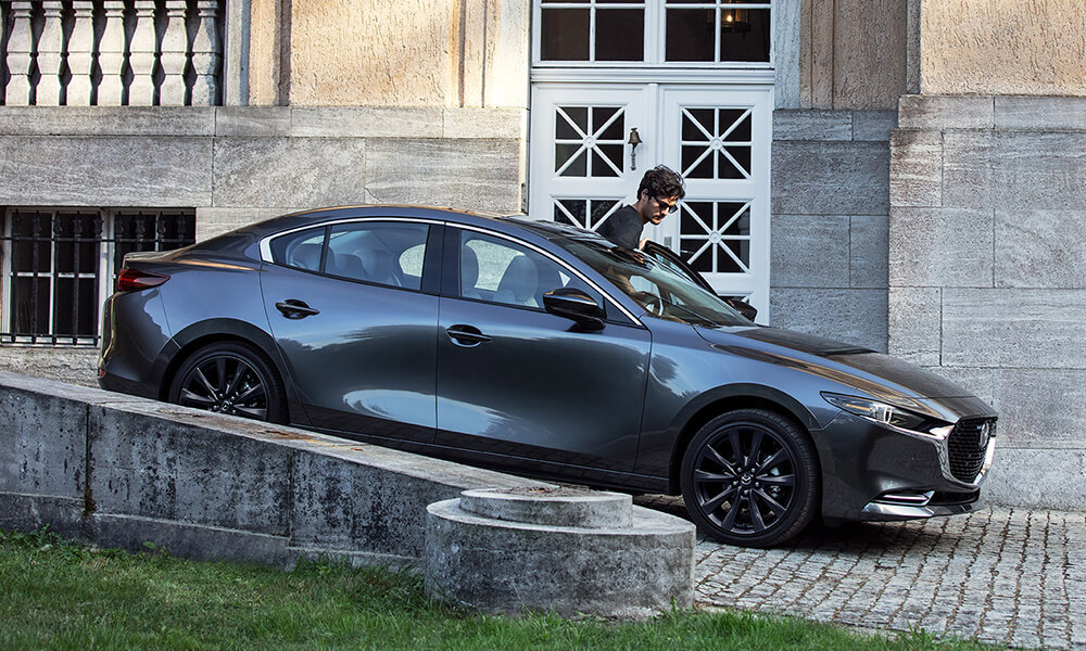 Side profile of a man entering a Machine Grey Metallic Mazda3.